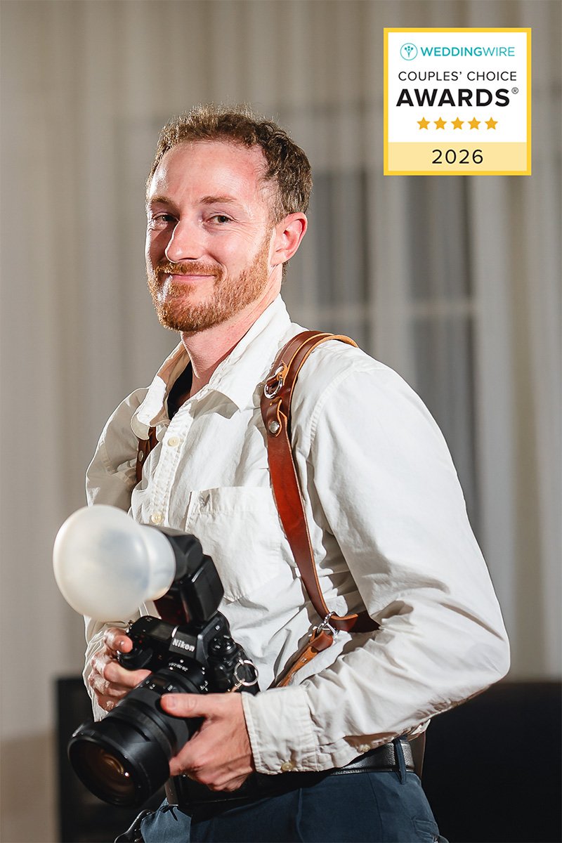 A man stands outdoors, holding a camera and preparing to take a photograph.