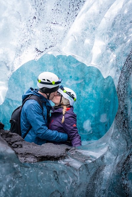 A man and woman share a kiss inside a dimly lit cave.