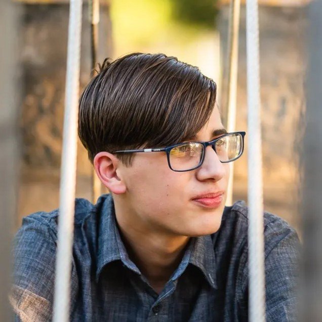A man with glasses is smiling and looking directly at the camera.